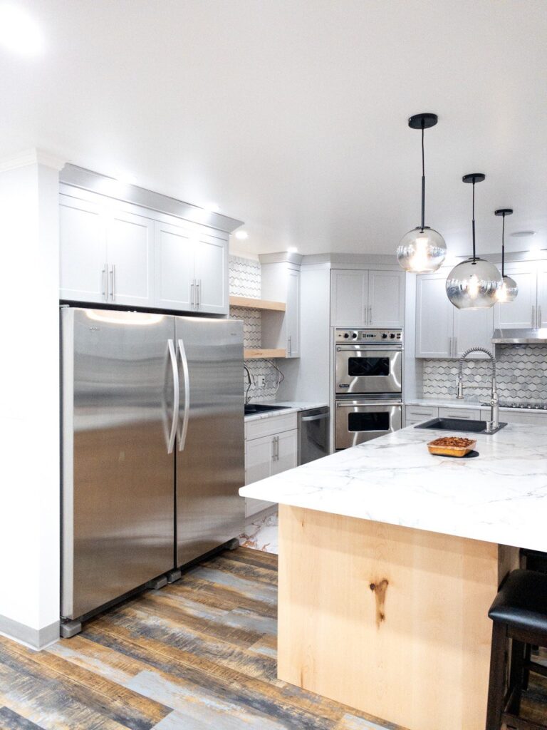 Contemporary kitchen featuring white cabinetry with marble countertops.