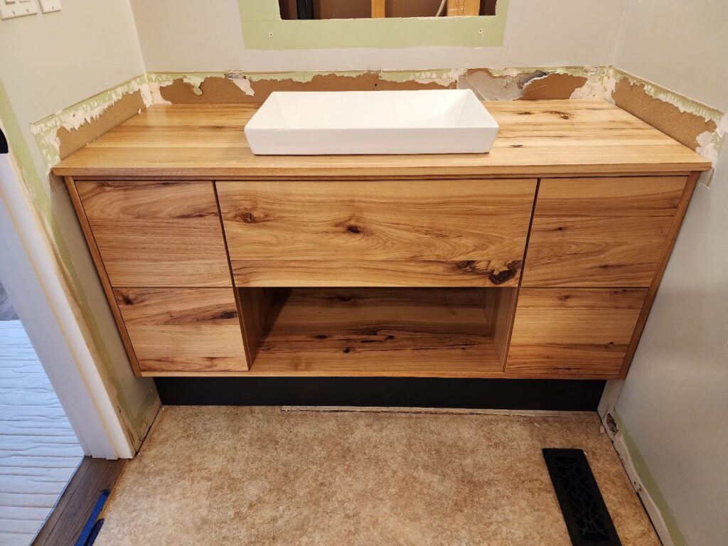 A wooden minimalistic bathroom storage with a sink on top