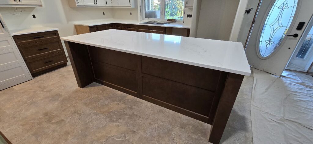 Spacious kitchen with white coloured cabinets and an island.